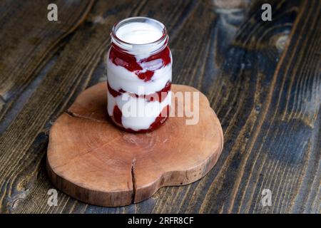 Yaourt fait à partir de lait frais avec l'ajout de confiture de fraise rouge sucrée, délicieux yaourt avec saveur de fraise Banque D'Images