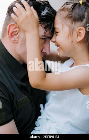 Portrait de petite fille ukrainienne rencontrant son père de la guerre pendant ses vacances et joyeuse l'embrasse. Guerre en Ukraine. Invasi militaire russe Banque D'Images