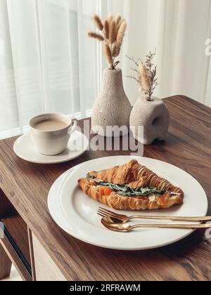 Croissant avec saumon et œufs brouillés avec café sur une table basse Banque D'Images