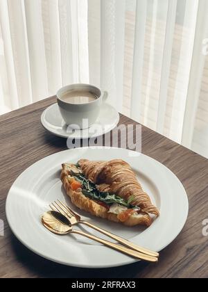 Croissant avec saumon et œufs brouillés avec café sur une table basse Banque D'Images