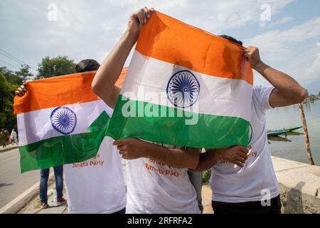 Srinagar, Inde. 04 août 2023. Les partisans du parti Bharatiya Janata (BJP) cachent leur visage derrière les drapeaux nationaux indiens alors qu'ils célèbrent le quatrième anniversaire de l'abrogation de l'article 370 et du statut spécial du Jammu-et-Cachemire lors d'une réunion publique à Srinagar. Le gouvernement du Premier ministre indien Narendra Modi a abrogé l'article 370 le 5 août 2019, mettant fin au statut semi-autonome spécial de la région. (Photo de Faisal Bashir/SOPA Images/Sipa USA) crédit : SIPA USA/Alamy Live News Banque D'Images