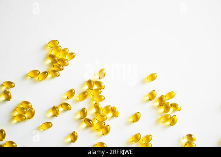 Soins de santé et concept de soutien immunitaire. Capsules molles de vitamine D3 sur une surface blanche. Gélules jaunes, vue de dessus, espace de copie. Nutritionnel Banque D'Images