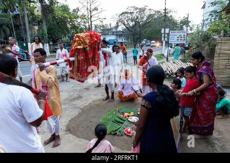 Famille debout devant leur maison offrant de la nourriture et allumant des bougies sur des assiettes, Kaziranga, Assam, Inde Banque D'Images