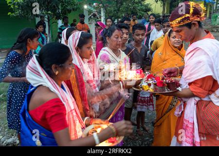 Famille debout devant leur maison offrant de la nourriture et allumant des bougies sur des assiettes, Kaziranga, Assam, Inde Banque D'Images