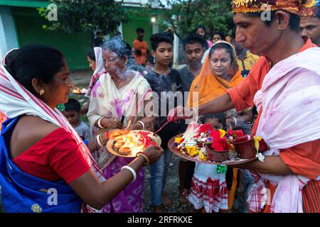 Famille debout devant leur maison offrant de la nourriture et allumant des bougies sur des assiettes, Kaziranga, Assam, Inde Banque D'Images