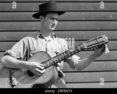 Jeune homme jouant de la guitare acoustique, Farm Security Administration camp de travail migratoire, Weslaco, Texas, USA, Arthur Rothstein, ÉTATS-UNIS Farm Security Administration, février 1942 Banque D'Images