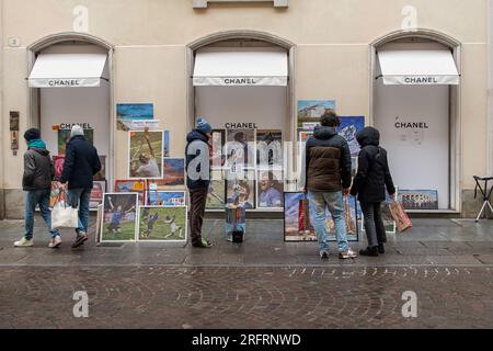 Un vendeur de rue vendant des affiches de sport devant le magasin de luxe fermé Chanel dans la rue via Lagrange en hiver, Turin, Piémont, Italie Banque D'Images