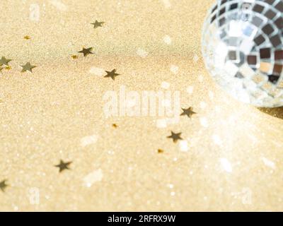 Carte de voeux - nouvel an ou Noël avec boule disco argentée et paillettes en forme d'étoile dorée sur fond brillant doré. Concept de vacances lumineux. Vue de dessus. Banque D'Images