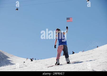 Mammoth Lakes, Californie. 4 juillet 2023. Un homme avec un drapeau américain monte son snowboard sous les gondoles à Mammoth Mountain ski Resort par une journée claire d'été Banque D'Images