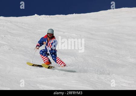 Mammoth Lakes, Californie. 4 juillet 2023. Un homme d'âge moyen avec une moustache et portant une combinaison de ski d'un seul tenant drapeau américain ski à Mammoth Mountain. Banque D'Images