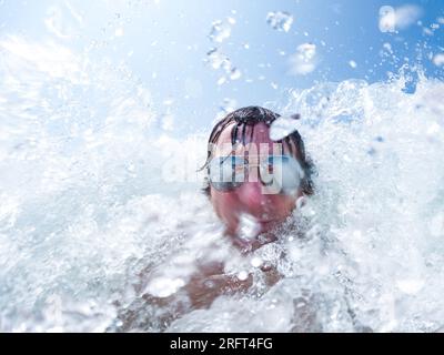 Vague éclaboussant sur la tête des hommes portant des lunettes de soleil dans le lac Banque D'Images