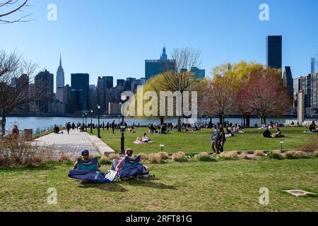 Rendez-vous ensoleillé avec vue sur les gratte-ciel de Manhattan. L'étreinte d'un couple au milieu d'un printemps florissant, où la nature encadre leur connexion urbaine. Banque D'Images
