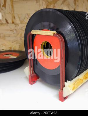 Une collection de disques vintage à 45 tours (années 45), présentés dans un rack en métal, avec des extras empilés à proximité. Étiquettes vierges Banque D'Images