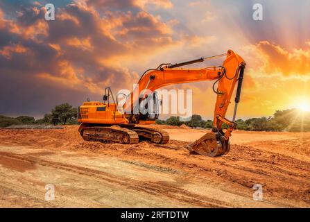 pelle jaune sur le chantier au coucher du soleil Banque D'Images