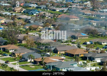Vue du dessus de la maison privée en feu sur le feu et les pompiers éteignant les flammes après un court-circuit causé pour enflammer le toit endommagé par un ouragan Banque D'Images