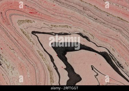 photo macro détaillée de papier marbrée dans des lignes fluides de tons rouges avec des stries noires, blanches et dorées entrelacées, beau fond abstrait Banque D'Images