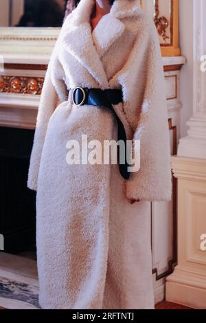 Détails de mode de long manteau chaud blanc avec ceinture noire. Tenue tendance, concept de vêtements féminins automne hiver. Banque D'Images