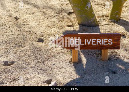 Panneau de livraison en bois avec flèche dans le sol. La flèche pointe vers la gauche. Espace pour copier l'espace. Banque D'Images