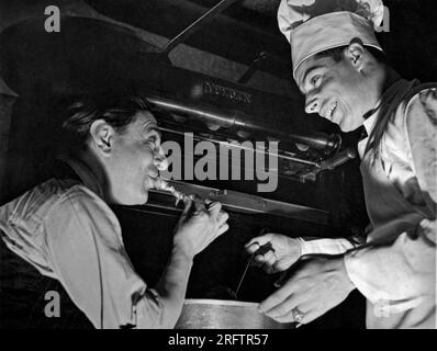 San Francisco, Californie : 14 décembre 1937. Le ténor de l'opéra Tito Schipa essaie la sauce spaghetti préférée du chef Joe DiMaggio lorsqu'il tombe au restaurant Yankee slugger's de San Francisco. Banque D'Images