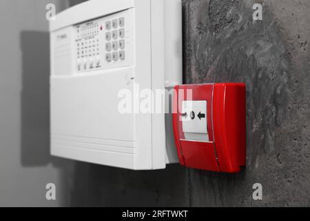 Bouton-poussoir d'alarme incendie et panneau de commande du système de sécurité de la maison sur le mur gris Banque D'Images