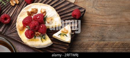 Savoureux fromage brie avec des framboises, des noix et du miel sur une table en bois, vue de dessus. Conception de bannière avec espace pour le texte Banque D'Images