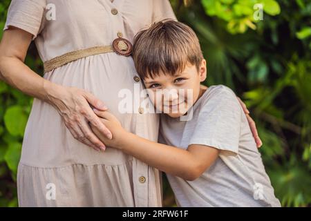 Un moment réconfortant capturé dans le parc alors qu'une femme enceinte après 40 partage un lien spécial avec son fils adolescent, embrassant la beauté de la mère Banque D'Images