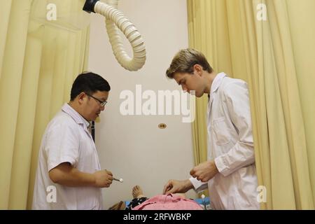 Zhengzhou, Chine. 06 août 2023. (230806) -- ZHENGZHOU, 6 août 2023 (Xinhua) -- Joel Mikael Walker (à droite) administre un traitement d'acupuncture à un patient alors que son mentor regarde dans un hôpital de médecine traditionnelle chinoise (MTC) à Zhengzhou, dans la province du Henan en Chine centrale, le 13 juillet 2023. Les habitants visitant un hôpital de médecine traditionnelle chinoise (MTC) à Zhengzhou dans la province du Henan en Chine centrale se trouvent souvent agréablement surpris lorsqu'ils reçoivent un traitement d'un praticien allemand qualifié spécialisé en acupuncture.TO GO WITH 'Across China : l'étudiant allemand devient sensation en ligne comme MTC Banque D'Images