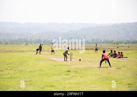 Garçons jouant au cricket sur le terrain Banque D'Images