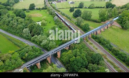 Un train des West Midlands Railways passe sous l'aqueduc historique d'Edstone, construit en fer en 1816, sur le canal Stratford-upon-Avon, dans le Warwickshire Banque D'Images