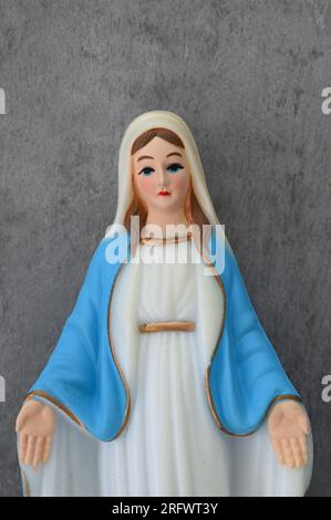 Modèle de Vierge Marie avec de grands yeux bleus semblant tristes et portant une robe bleue avec des mains accueillantes Banque D'Images