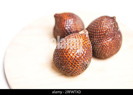 Salak ou fruit de serpent dans la plaque de bois isolé sur fond blanc. Banque D'Images