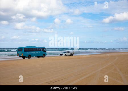 75 km de la plage sur Fraser Island K'gari avec bus explorateur et véhicule 4WD conduisant sur la route de sable à côté de l'océan, Queensland, Australie Banque D'Images