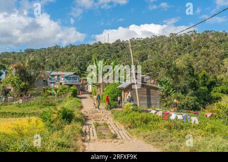 Andasibe, Madagascar - 26.2023, mai : les gens marchent le long de la route à Andasibe, maisons en bois de fond Banque D'Images