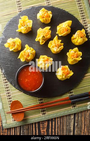 Gros plan de Shumai ou Shaomai ou Siu Mai ou Siomay est un type de Dumpling traditionnel chinois cuit à la vapeur servi avec de la sauce Chili sur la table. Vertical à Banque D'Images