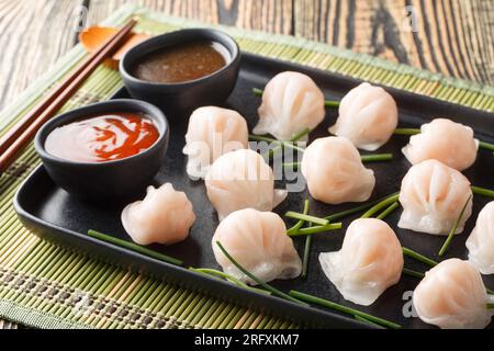 Boulettes chinoises traditionnelles à la vapeur Dim sums Har gow avec crevettes servies avec sauce gros plan sur la table. Horizontal Banque D'Images