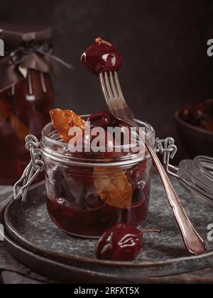 Prunes marinées aux épices dans un pot en verre sur la table de cuisine Banque D'Images