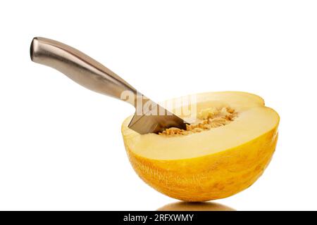 Une moitié d'un melon jaune avec un couteau en métal, macro, isolé sur un fond blanc. Banque D'Images