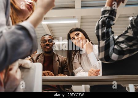 Beaux collègues hommes noirs et femmes blanches écoutant leurs collègues confronter des idées tout en travaillant ensemble Banque D'Images
