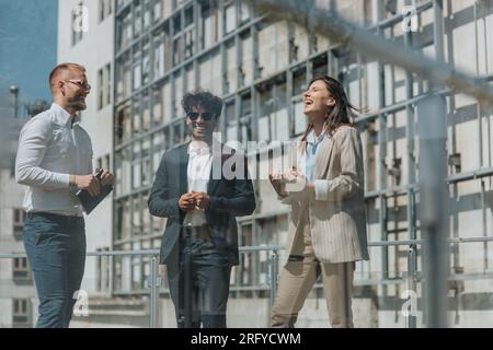 Des ingénieurs de construction heureux et débordés de joie ayant une conversation amusante tout en travaillant dans la ville par une journée ensoleillée Banque D'Images