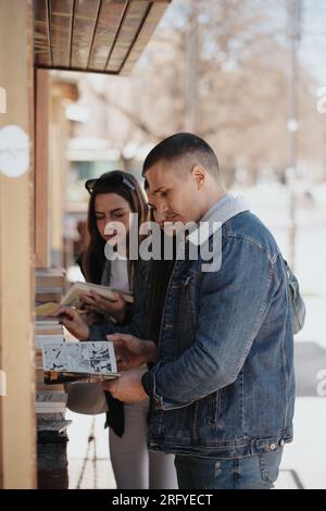 Bel homme regardant le livre de bande tout en se tenant avec ses amis à la librairie Banque D'Images