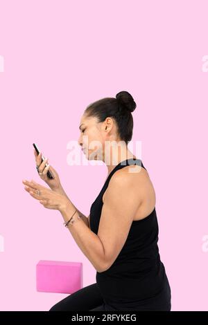 Trauma libérant des exercices, femme âgée dans sa soixantaine , lisant sur le téléphone des exercices pour la récupération de traumatisme . Banque D'Images