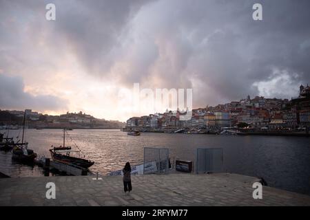 Enchantement au bord de la rivière de Porto au coucher du soleil : une toile à couper le souffle peinte avec des teintes radieuses sur le Douro, tissant la beauté urbaine et naturelle Banque D'Images