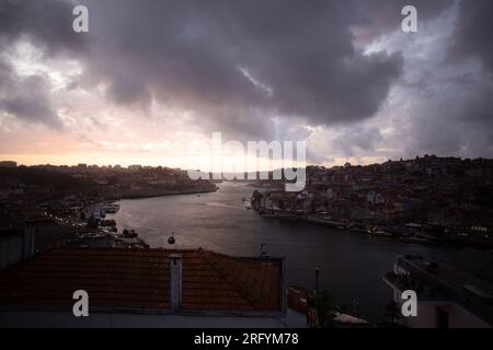 Enchantement au bord de la rivière de Porto au coucher du soleil : une toile à couper le souffle peinte avec des teintes radieuses sur le Douro, tissant la beauté urbaine et naturelle Banque D'Images