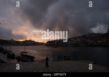 Enchantement au bord de la rivière de Porto au coucher du soleil : une toile à couper le souffle peinte avec des teintes radieuses sur le Douro, tissant la beauté urbaine et naturelle Banque D'Images