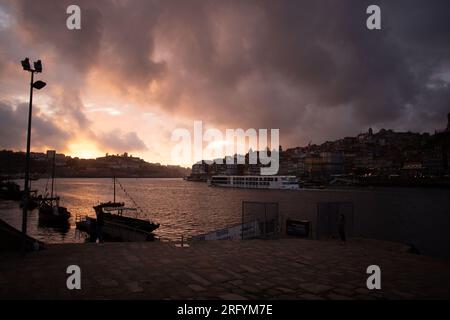 Enchantement au bord de la rivière de Porto au coucher du soleil : une toile à couper le souffle peinte avec des teintes radieuses sur le Douro, tissant la beauté urbaine et naturelle Banque D'Images
