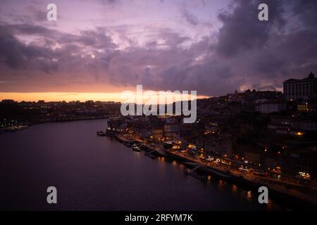 Enchantement au bord de la rivière de Porto au coucher du soleil : une toile à couper le souffle peinte avec des teintes radieuses sur le Douro, tissant la beauté urbaine et naturelle Banque D'Images