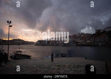 Enchantement au bord de la rivière de Porto au coucher du soleil : une toile à couper le souffle peinte avec des teintes radieuses sur le Douro, tissant la beauté urbaine et naturelle Banque D'Images