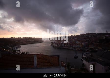 Enchantement au bord de la rivière de Porto au coucher du soleil : une toile à couper le souffle peinte avec des teintes radieuses sur le Douro, tissant la beauté urbaine et naturelle Banque D'Images