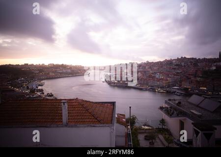 Enchantement au bord de la rivière de Porto au coucher du soleil : une toile à couper le souffle peinte avec des teintes radieuses sur le Douro, tissant la beauté urbaine et naturelle Banque D'Images