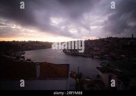 Enchantement au bord de la rivière de Porto au coucher du soleil : une toile à couper le souffle peinte avec des teintes radieuses sur le Douro, tissant la beauté urbaine et naturelle Banque D'Images